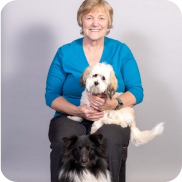 Diane from Partner Dogs Canada smiling while sitting with two therapy dogs during a professional team photo session.