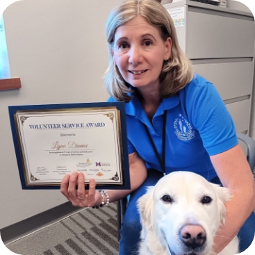 Lynn Dineen from Partner Dogs Canada holding her Volunteer Service Award beside her certified therapy dog.