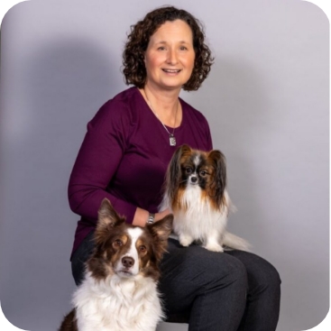 Nancy from Partner Dogs Canada posing with two trained therapy dogs during an official team photo session.